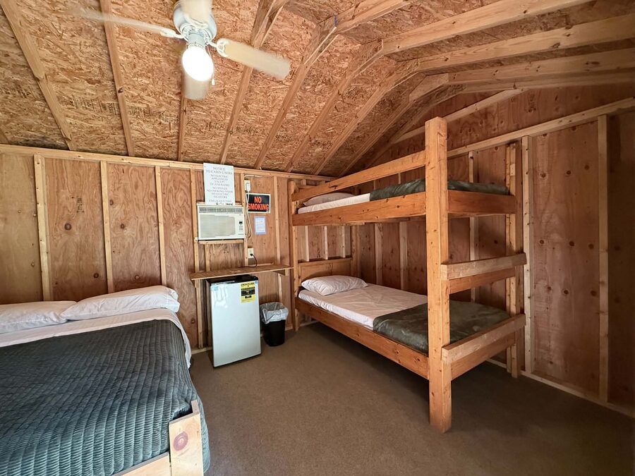 Twin bunk beds, double bed, mini fridge and air conditioner inside a rustic cabin
