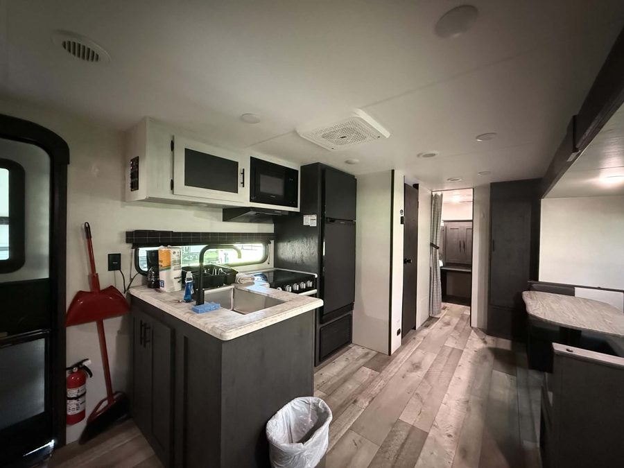 Kitchen with sink, stove, microwave and refrigerator inside the bunkhouse RV rental